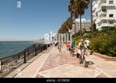 people walking and cycling, Marbella promenade ( Paseo Maritimo ), Marbella, Costa del Sol, Andalusia Spain Europe Stock Photo