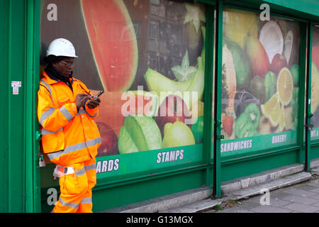 Workman using his mobile phone on a street in King's Cross Stock Photo