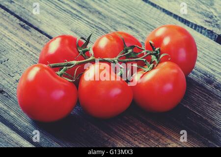 Fresh tomatoes on vine one wooden table. Toned image Fresh tomatoes on vine one wooden table. Toned image