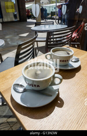 Two cups of coffee on a table in a branch of Costa.  Showing the Costa logo on the cups. The company is owned by Whitbread. Stock Photo