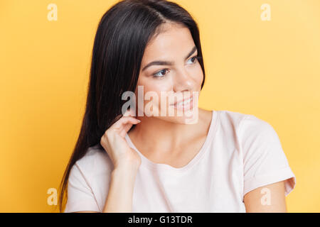Smiling beautiful woman looking away over yellow background Stock Photo