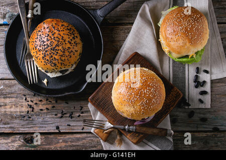 Three Homemade veggie burgers with sweet potato, black rice and red beans, served on wooden chopping board over old wooden table Stock Photo