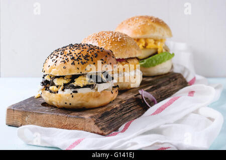 Three Homemade veggie burgers with sweet potato, black rice and red beans, served on wooden chopping board with kitchen towel ov Stock Photo