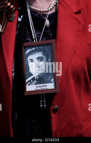 Jerusalem, Israel. 8th May, 2016. A relative of a Russian-Israeli World War II veteran wearing his portrait during a parade in honor of 71 years since the Allies’ victory over Nazi Germany in World War II, in the center of Jerusalem Credit:  Eddie Gerald/Alamy Live News Stock Photo