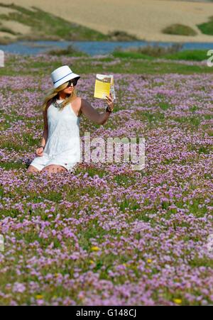 Dorset, UK. 8th May, 2016. One young woman has found how amazingly colourful the UK countryside can be at this special time of the year and when the sun shone today (Sun) even better! Laura Dean (26) pictured enjoying each of three vibrant and vivid displays located, within a few miles of her home at Weymouth, Dorset. The 5acre carpet of, Sea Pinks (Thrift) are next to the 18mile long Chesil Beach, one of the largest such areas of the plants in the UK.  Credit:  Dorset Media Service/Alamy Live News Stock Photo