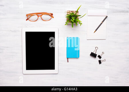 Top view of a tablet computer and office items on a white wooden desk. Home office concept. Business and lifestyle. Copyspace. Stock Photo