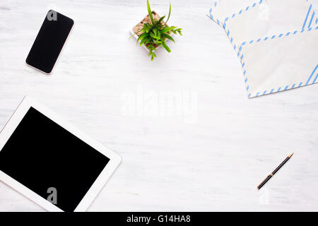 Top view of a tablet computer, smartphone and office items on a white wooden desk. Home office concept. Business and lifestyle. Stock Photo