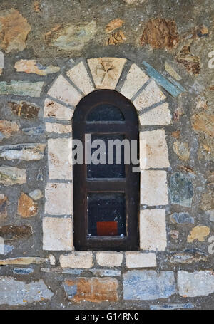 Ancient Rounded Stone An ancient stone wall with a small arch surrounds a Mediterranean ...