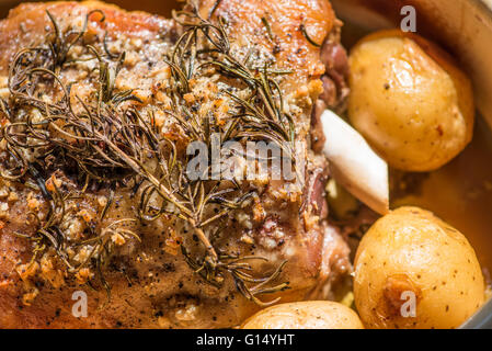 Roast shoulder of lamb being cooked with roast potatoes Stock Photo