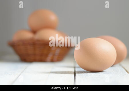 Some eggs in a basket on a white wooden table in a rustic kitchen. Empty copy space for editor's text. Stock Photo