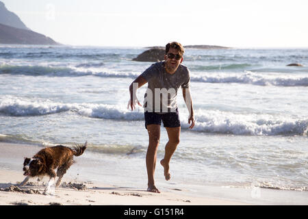 Man and dog playing on the beach Stock Photo