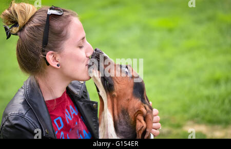 Young woman with an affectionate one year old Basset hound (Canis lupus familiaris) in the yard of a hobby farm. Stock Photo