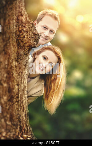 happy young couple standing behind tree and having fun Stock Photo