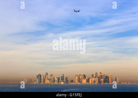 Jet airplane after take off from Hamad International Airport, seen above Doha city skyline from the sea, Qatar, Middle East Stock Photo