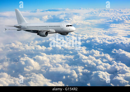 Commercial passenger plane flying above clouds Stock Photo