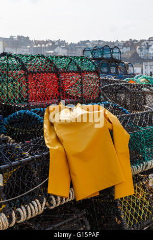 Trawlerman's protective oilskin smock, and lobster pots in the harbour. In Scarborough, England. Stock Photo