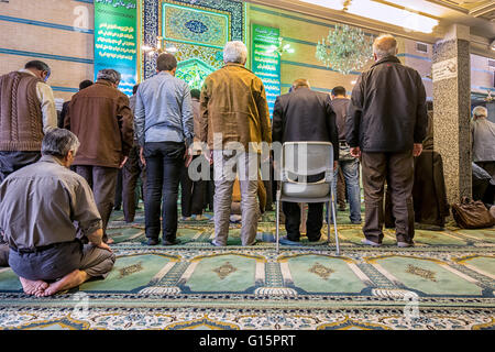 Busy Muslim businessmen take a break for prayer in a neighborhood prayer room that substitutes for a mosque when the mosque is too far away for five prayers a day. Stock Photo