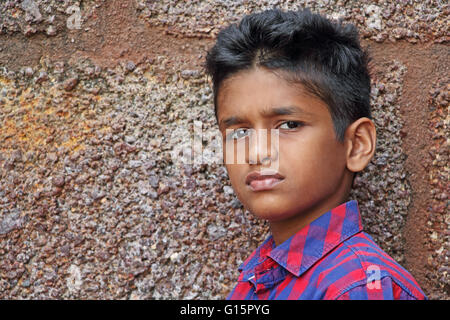 Teenage boy in angry and upset mood, red brick wall background Stock Photo