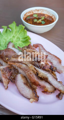 Sliced grilled beef steak with green leaves salad on pink dish served with chili sauce Stock Photo