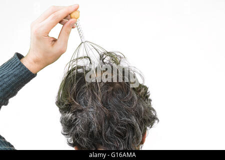 Man relaxes with the Genie head massager. Alternative Therapy. Indian head massage tool, self head massager. Stock Photo