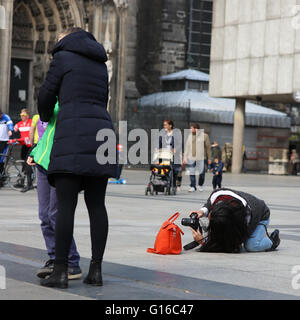 Woman lying on ground to take a photo of Cologne cathedral, Germany, crop of G16C42