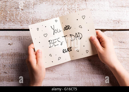 Fathers day composition. Hands of dad holding greeting card Stock Photo