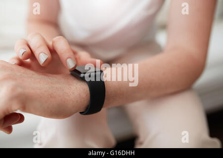 Closeup shot of caucasian female checking time on her smart watch. Focus on wrist watch and hands.
