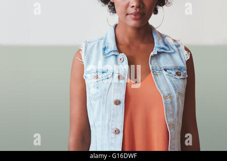 Cropped image of young african woman in stylish casuals. She is wearing a sleeveless denim shirt. Stock Photo