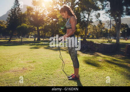 Full length shot of fit young woman with skipping rope outdoors at the park. fitness female holding a jump rope for workout on s Stock Photo