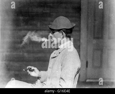 Entitled: 'A whiff of comfort' shows a man smoking a cigar. Kineo House, Moosehead Lake, Maine. A cigar is a tightly-rolled bundle of dried and fermented leaf tobacco which is rolled in a series of types and sizes that is ignited so that its smoke may be Stock Photo