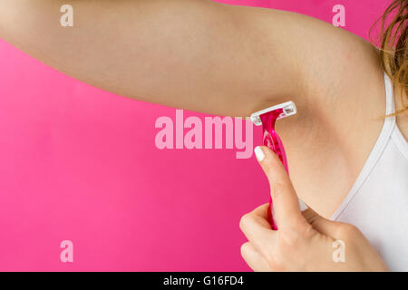 Woman shaving her armpit with a red shaver Stock Photo