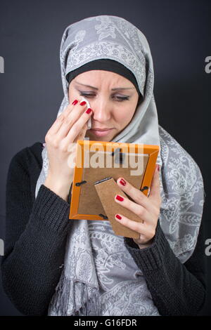 Muslim woman moaning over an old photograph in a frame Stock Photo