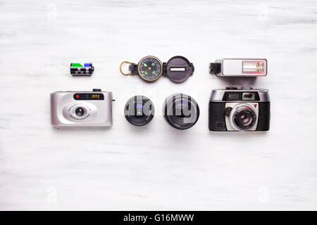 Top view of collection of vintage cameras on a white wooden table, with a compass. Nostalgic and travel concept. Stock Photo