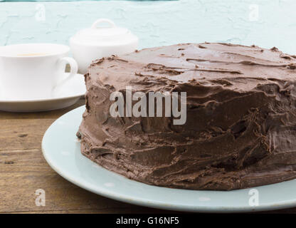 Chocolate cake close up on blue plate on rustic wood table with tea cup Stock Photo