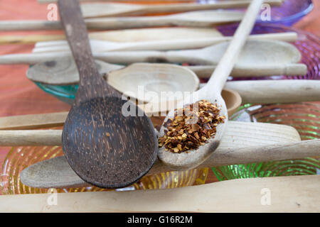 crushed red peppers on a wooden spoon with nearby others wooden spoons arranged in row Stock Photo