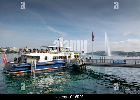 Cruising boat docking at Geneva lake with jet d'eau in the background on a beautiful day, Switzerland Stock Photo