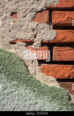 Crumbled gray green plaster on a brick wall Stock Photo