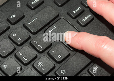 finger pressing enter on a keyboard Stock Photo