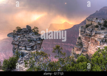 The sun lights up the low clouds and swirling snow seen from Mather Point in Grand Canyon National Park, Arizona. Stock Photo