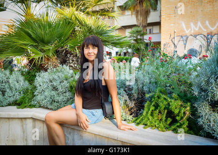 girl sitting smiling on a bench in a seaside town near Rome Stock Photo