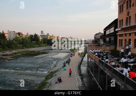 People relax at the Kamo river riverbank in the central of Kyoto, Japan. Stock Photo