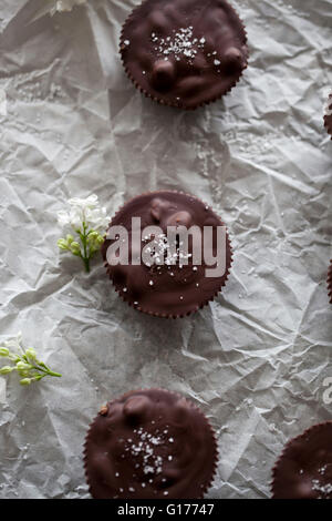 Chocolate cups filled with date caramel with sea salt on a white paper Stock Photo