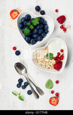 Healthy breakfast of muesli, berries with yogurt and seeds on white background -  Healthy food, Diet, Detox, Clean Eating or Veg Stock Photo