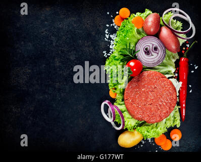 Raw Ground beef meat Burger steak cutlets with seasoning and vegetables on vintage  board Stock Photo