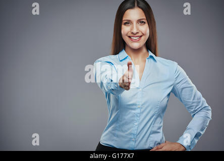 Friendly young businesswoman making a handshake gesture against a gray background Stock Photo