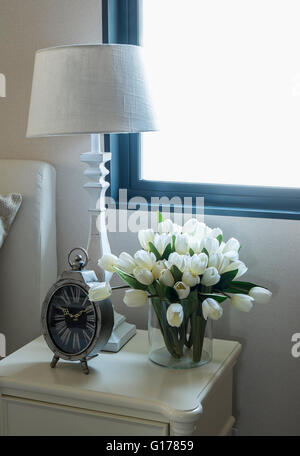 white lamp and alarm clock on bedside table Stock Photo