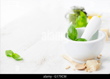 Ceramic Mortar with Pestle and Pesto ingredients over white Stock Photo