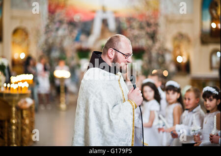 LVIV, UKRAINE - MAY 8, 2016: Priest at ceremony of a First Communion in the Church of St. Peter the Great of Ukrainian Greek Cat Stock Photo