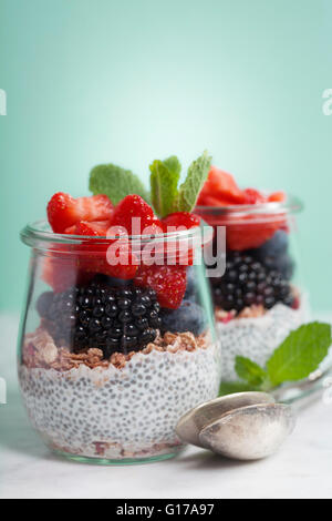 Chia seeds vanilla pudding and berries on blue background - Healthy food, Diet, Detox, Clean Eating or Vegetarian concept. Stock Photo
