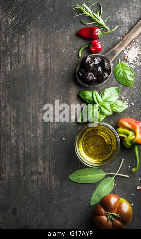 Food background with vegetables, herbs and condiment. Greek black olives, fresh basil, sage, rosemary, tomato, peppers, oil on d Stock Photo